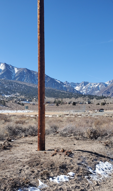 a power pole in the mountains has the ground around its perimeter cleared as a fuels reduction project